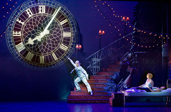 Production image from Matthew Bourne's Cinderella, showing the clock ticking towards midnight as Cinderella watches on.