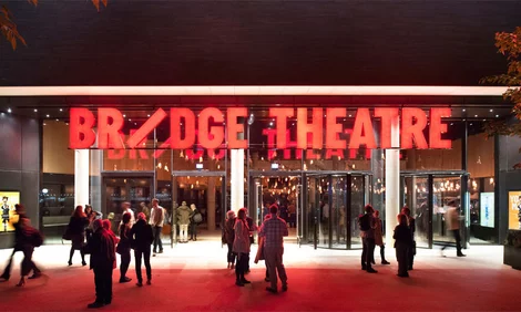 Bridge Theatre London exterior at night, with theatregoers outside