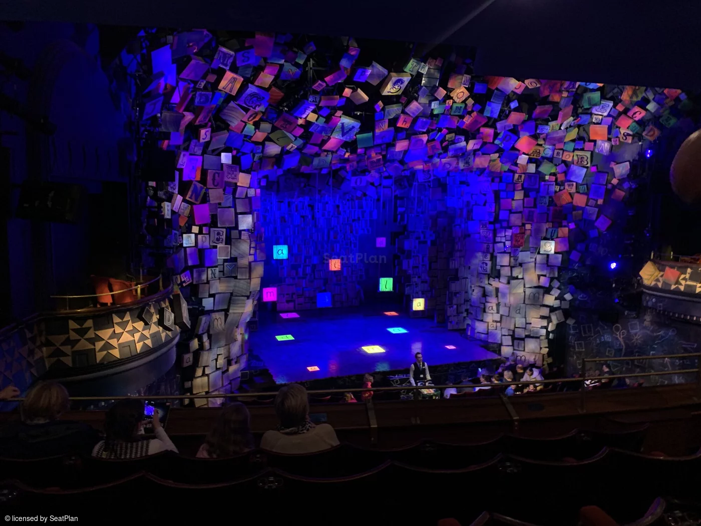 A seat view from the dress circle. It shows the colourful alphabet set, which spells out the word 'Matilda' in the centre of the stage.